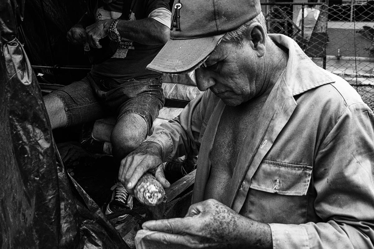 Ricardo compra yucas a un vendedor ambulante. Una vecina se acerca con la ilusión de comprar cebollas y se aleja maldiciendo el precio (Foto: Sadiel Mederos Bermúdez). 