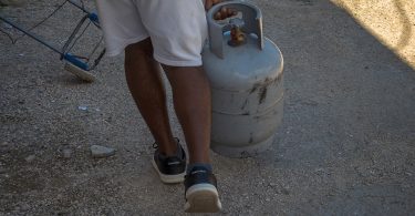 Hombre en Cuba transportando un cilindro de gas licuado para uso doméstico.