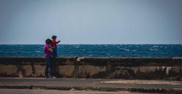 Madre con su hijo observando el mar desde el Malecón de La Habana.