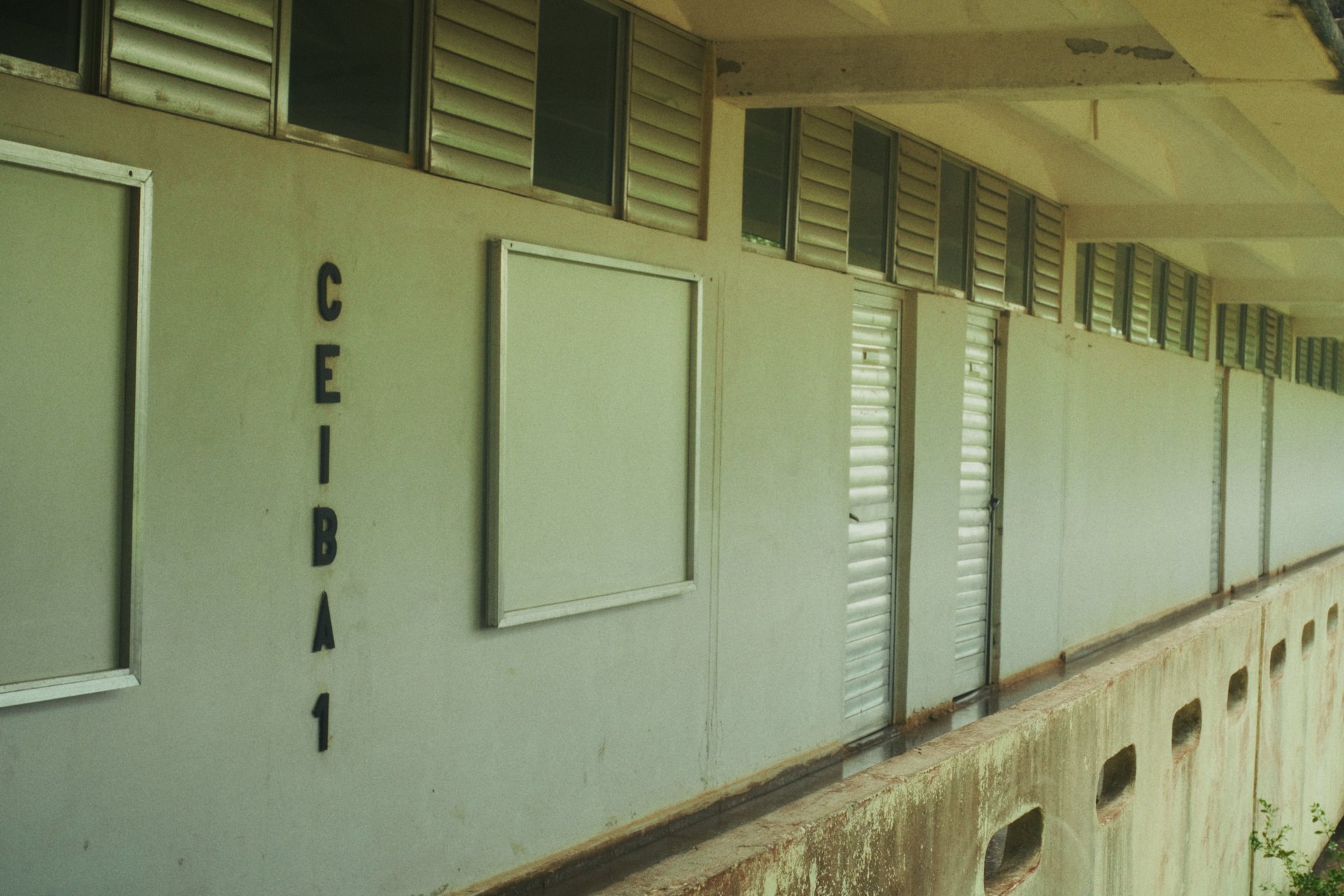 Fachada principal del Instituto Preuniversitario en el Campo Ernesto Guevara, con ventanas de persianas metálicas y el nombre "Ceiba 1" en la pared.