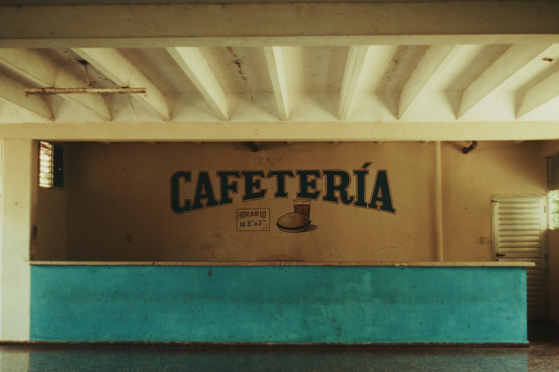  Interior de la cafetería de Ceiba 1 con una barra azul y un letrero en la pared.