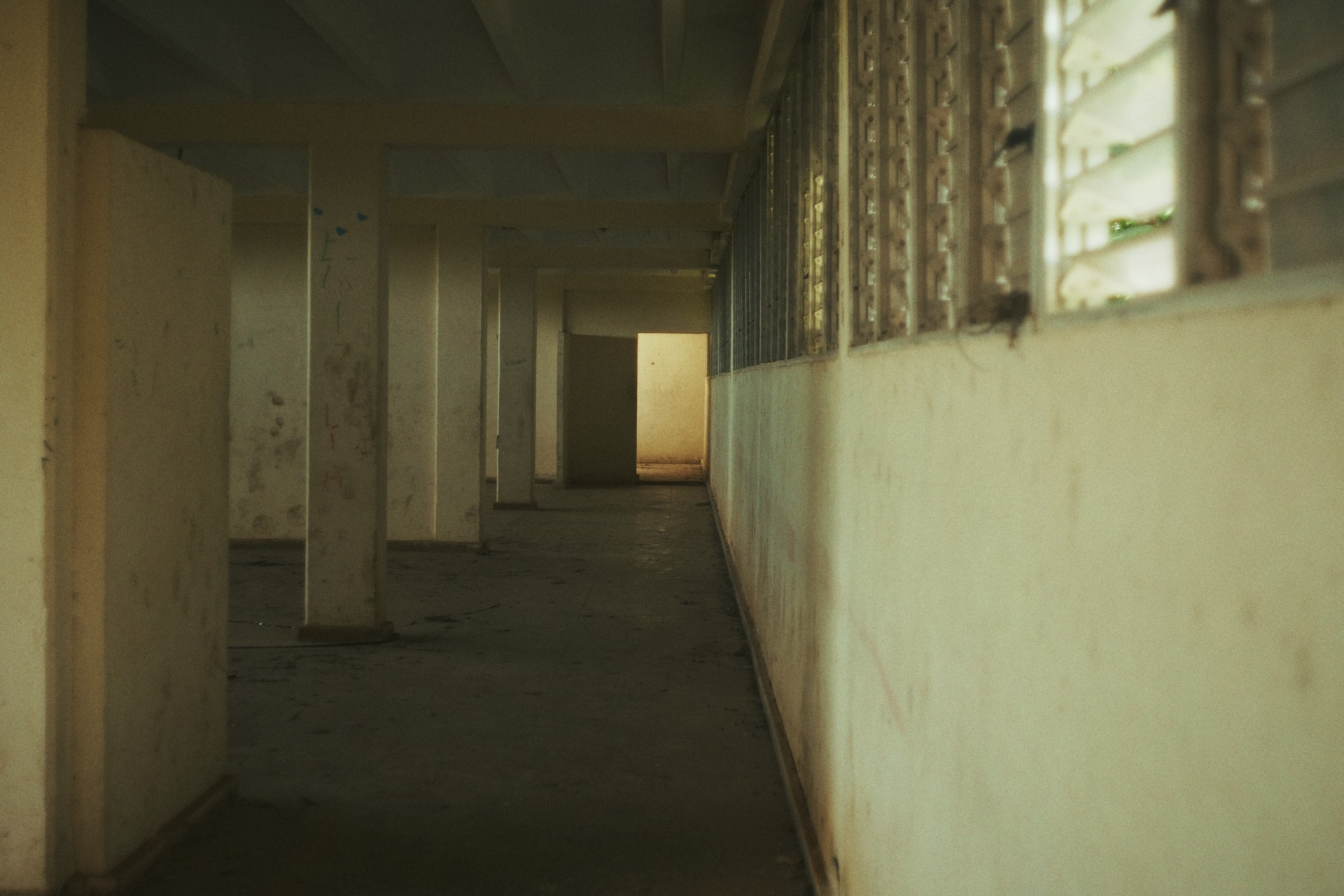 Pasillo interior de los albergues estudiantiles de Ceiba 1, con paredes desgastadas y luz al fondo.